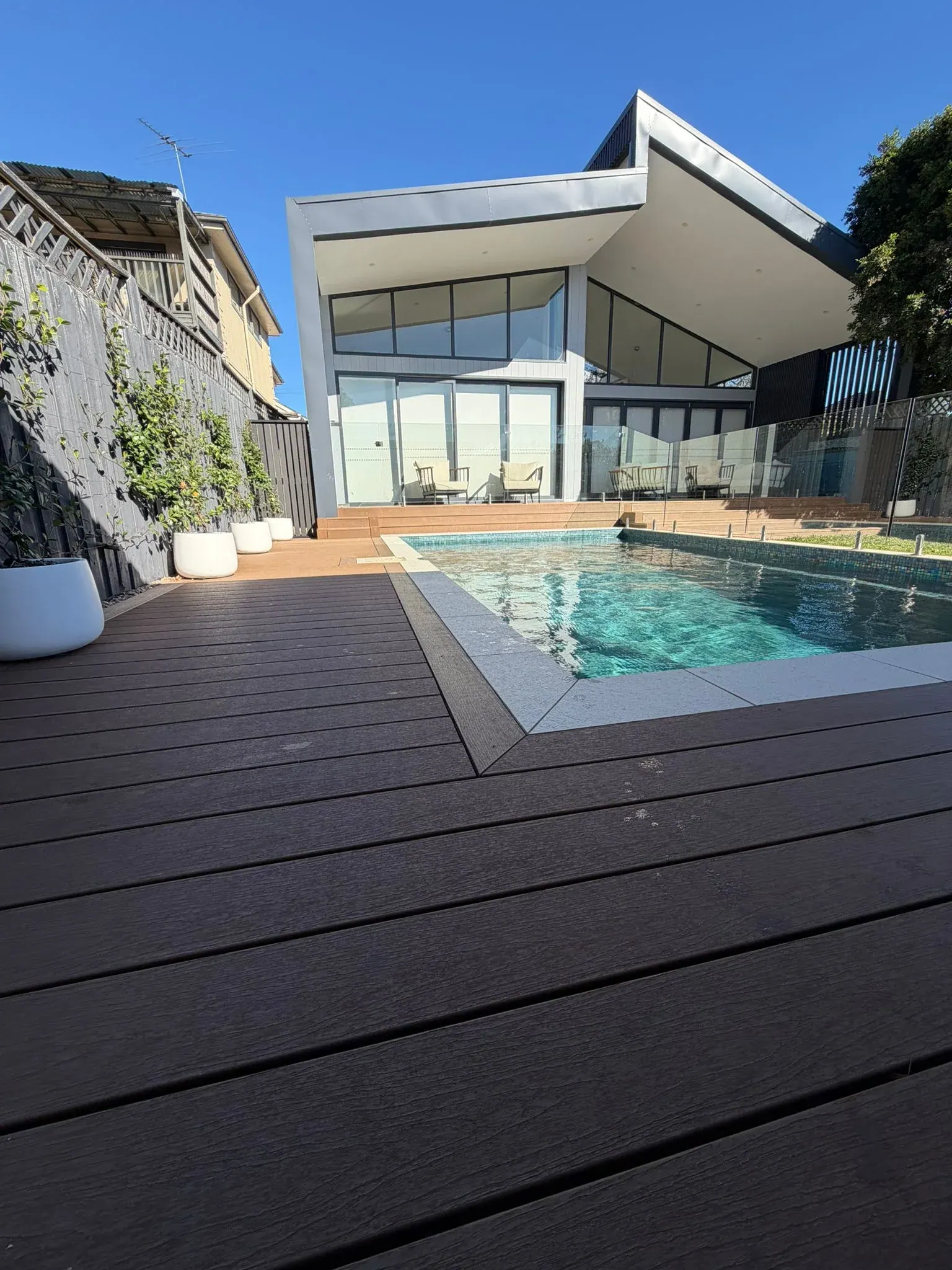 Modern timber-clad home opening onto a designed lawn at dusk